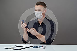 Man checking blood sugar level with glucometer on gray background