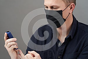 Man checking blood sugar level with glucometer on gray background