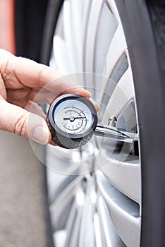 Close-Up Of Man Checking Car Tyre Pressure With Gauge