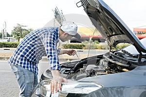Man checking engine lube oil level under car hood, fix broken car on the street