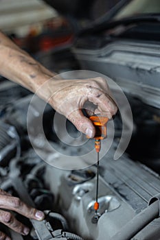 A man is checking the engine oil on a car for a replacement.