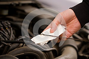 A man checking the engine oil level in a car using a dipstick