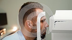 A man Checking Eye Vision On Optometry Equipment. Eyesight Exam