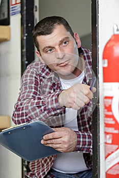 man checking fire extinguisher writing on document
