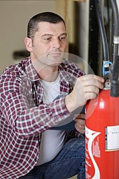 man checking fire extinguisher writing on document