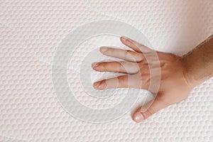 Man checking firmness of mattress, closeup