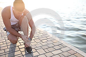 Man checking fitness tracker during training near river. Space for text