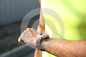 Man checking fitness tracker after training outdoors, closeup