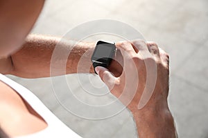 Man checking fitness tracker after training outdoors, closeup