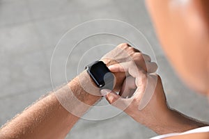 Man checking fitness tracker after training outdoors, closeup