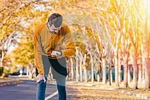 Man checking his smart fitness watch while runnning outtdoors at fall