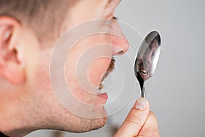 man checking his teeth after meal looking on his reflection in spoon.