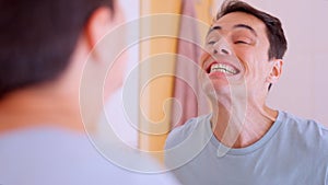 Man checking his teeth in the mirror after brushing