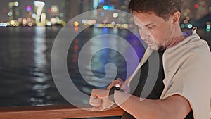 man checking notifications on smartwatches when walking in city in night, portrait of device user