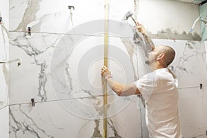 Man checking proper ceramic tile installation with level on wall, closeup. Building and renovation works photo