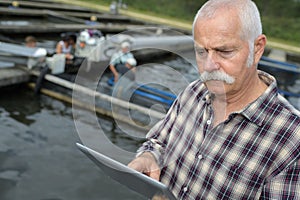 Man checking tablet at fishfarm photo