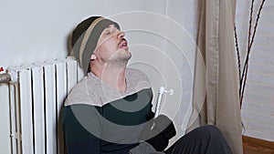 Man checking the temperature of the heating battery. Cold winter, cold in the house, apartment. A man warms himself near