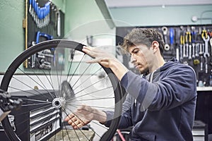 Man checking the tension of the spokes of a bicycle wheel in his bike workshop