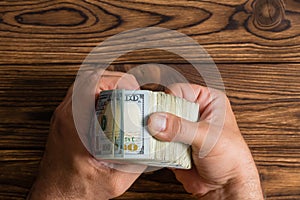 Man checking a thick stack of 100 dollar bills