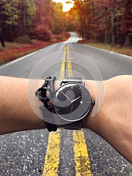 Man checking time on the stylish watch at scenic forest road.