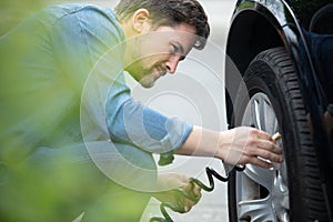 man checking tyre pressure with gauge