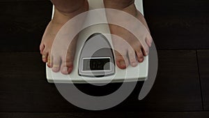 Man checking weight loss on scales, unhealthy nutrition, genetic predisposition photo