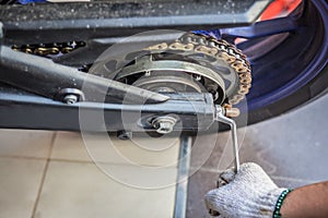 Man checks and Adjustments motorcycle chain on motorbike