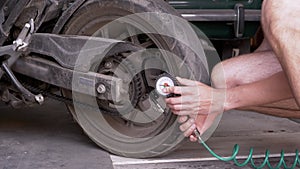 A Man Checks the Air Pressure in a Motorcycle Tire with a Pressure Gauge