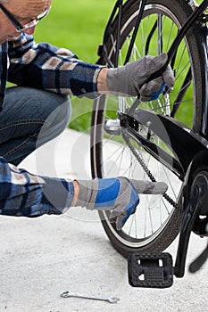 The man checks the chain from the bicycle