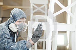 Man checks the evenness of the paint application in respiratory mask. Application of flame retardant ensuring fire