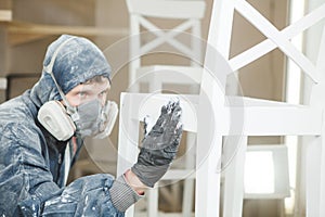 Man checks the evenness of the paint application in respiratory mask. Application of flame retardant ensuring fire photo
