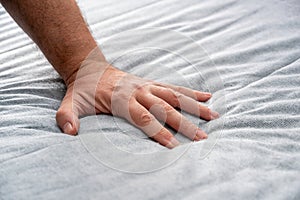 The man checks the quality and softness of the new mattress he will buy by pressing it with his hand