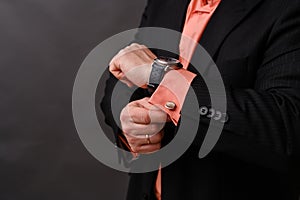 the man checks the time on his wristwatch. a businessman in a suit looks at his watch.