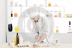 Man Chef baking dough with rolling pin in kitchen