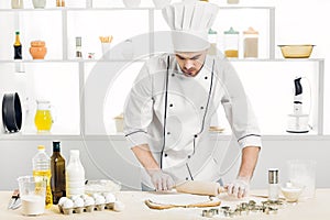 Man Chef baking dough with rolling pin in kitchen