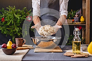 Man chef in a black apron kneading the dough with hands for Christmas baking. Joyful cooking for festive new year table