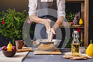 Man chef in a black apron kneading the dough with hands for Christmas baking. Joyful cooking for festive new year table