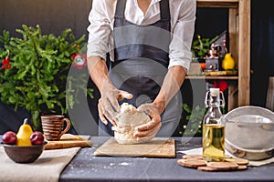 Man chef in a black apron kneading the dough with hands for Christmas baking. Joyful cooking for festive new year table