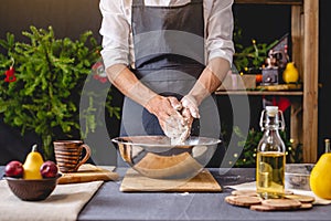 Man chef in a black apron kneading the dough with hands for Christmas baking. Joyful cooking for festive new year table