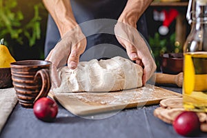 Man chef in a black apron kneads the dough with hands for Christmas baking. Joyful cooking for festive new year table