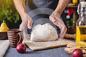 Man chef in a black apron kneads the dough with hands for Christmas baking. Joyful cooking for festive new year table