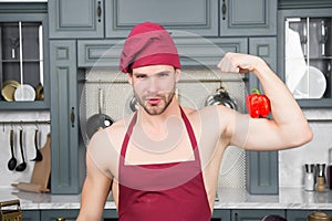 Man in chef hat, apron flex hand muscles with pepper