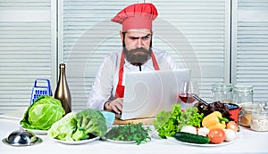 Man chef searching internet recipe cooking food. Chef laptop read culinary recipes. Culinary school. Hipster in hat and