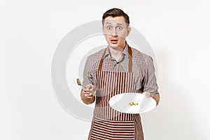 Man chef or waiter in striped brown apron, shirt holding white round clear plate with few green wet peas isolated on