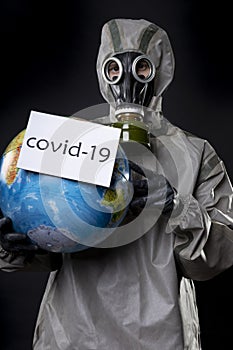 Man in a chemical protection suit and a gas mask. The guy is holding a model of the Earth, a globe. A placard with the