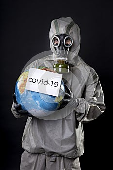 Man in a chemical protection suit and a gas mask. The guy is holding a model of the Earth, a globe. A placard with the