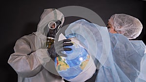 Man in a chemical protection suit and a gas mask. The guy is holding a model of the Earth, a globe. young woman in