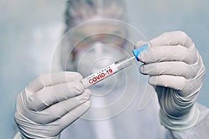 A man in a chemical protection suit holds a test tube for analysis. COVID-19. Coronavirus swab sample COVID-19. swab coronavirus