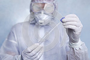 A man in a chemical protection suit holds a test tube for analysis. COVID-19. Coronavirus swab sample COVID-19. swab coronavirus