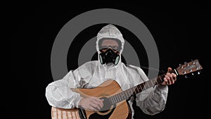 A man in a chemical protection suit plays the guitar